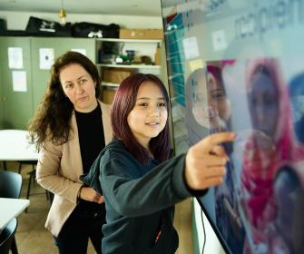 Sixth Form student and teacher looking at digital white board in classroom