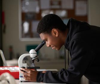 Sixth Form student looking into microscope in Science lab