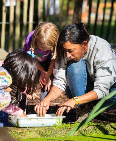 Children & Teacher inspecting their findings from a pond