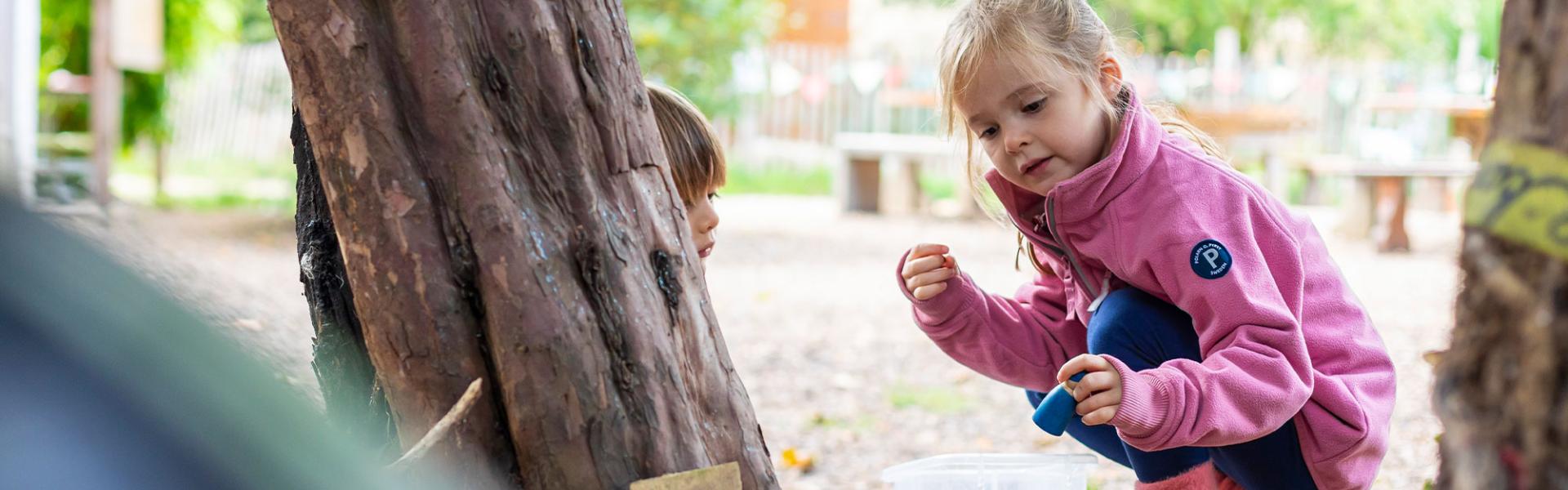Nursery children playing outdoors under trees